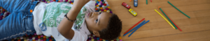 young boy laying on floor with toys