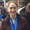 Woman standing at race finish line with medal