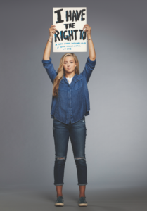 Chessy Prout holding a white posterboard that says "I have the right to" with a list of her rights