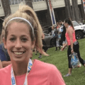 woman in a pink shirt smiling after finishing a running race