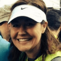 Woman with a white visor smiling at camera after finishing a marathon
