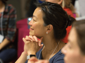 A woman looks off to the left, listening to a speaker off-camera