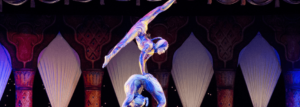 One acrobat balances on top of another, who is bent over in a bridge shape.