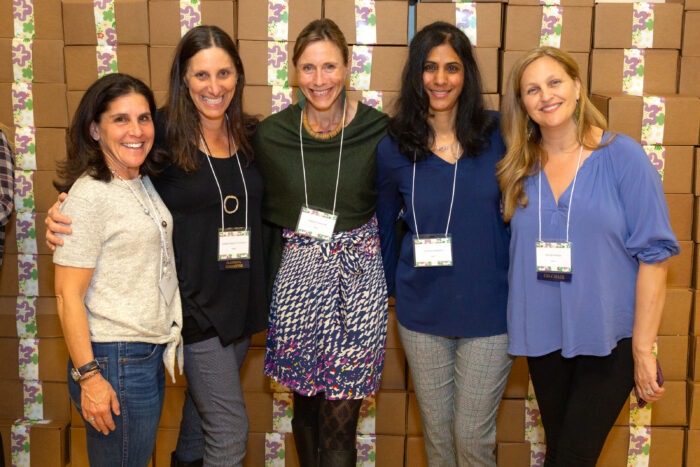 Women standing in front of packaged Hand in Hand boxes at the Hand in Hand event in 2019
